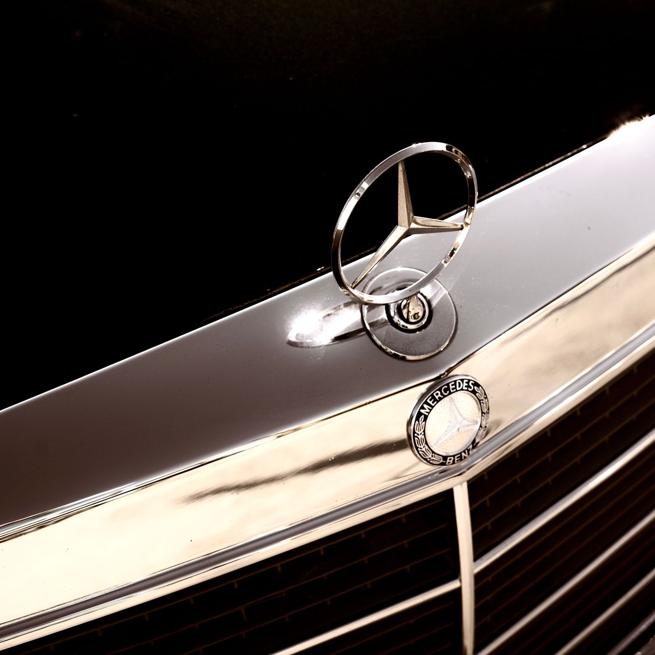 The star emblem of Mercedes-Benz in chrome on a car hood